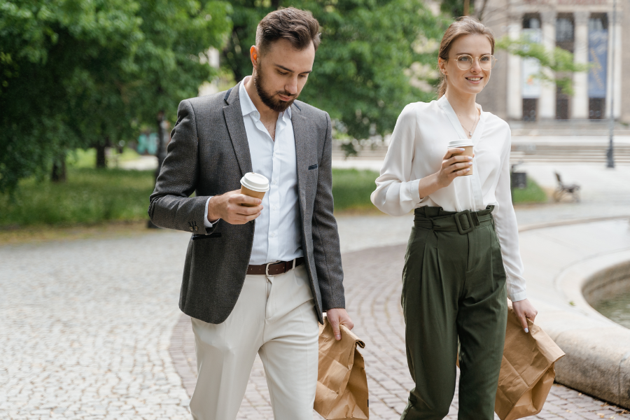Male and female co-workers walking with coffees