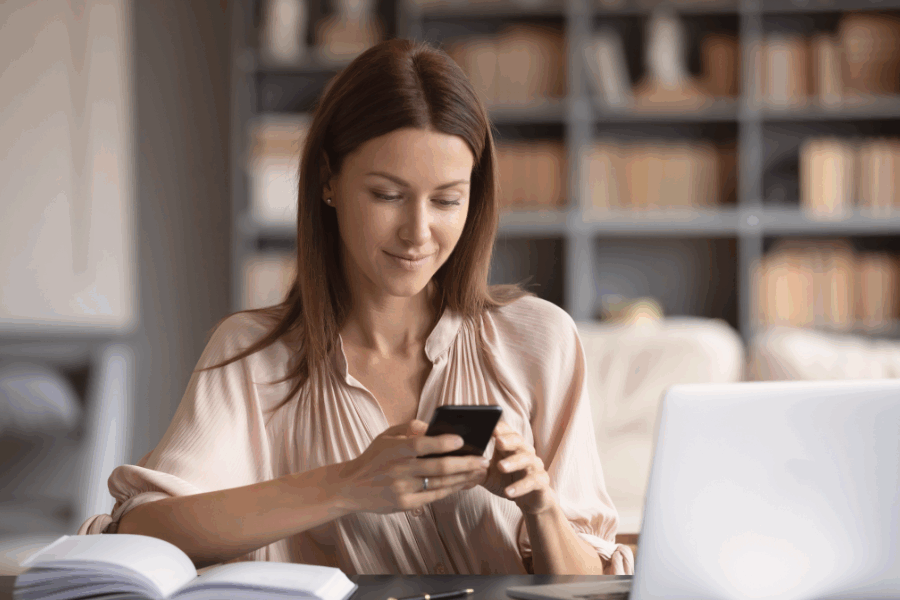 Woman on her phone while sitting at her desk